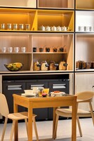 Una cocina moderna con armarios de madera, horno empotrado y comedor con mesa y sillas.