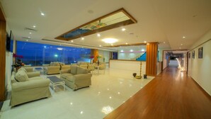 A spacious hotel lobby with a high ceiling, a reception desk, and a long hallway leading to other areas. - Bay View Hotel (Visakhapatnam)