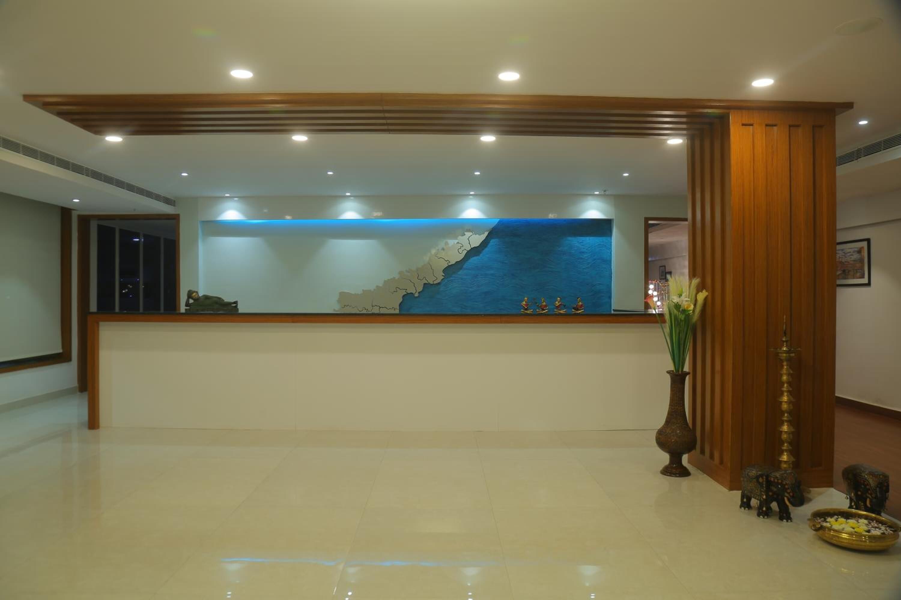 A reception desk with a blue ocean mural, a vase with flowers, and elephant statues.