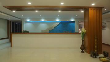 A reception desk with a blue ocean mural, a vase with flowers, and elephant statues.
