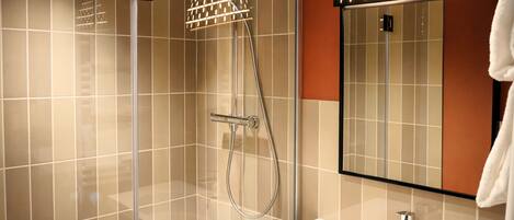 A modern bathroom with a glass shower enclosure, a white sink, and a large mirror.