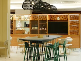 Una cocina moderna con una isla central, asientos tipo bar y un televisor grande.