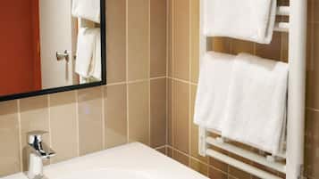 A bathroom with a white sink, a towel rack with multiple towels, a mirror with lights, and a digital display.