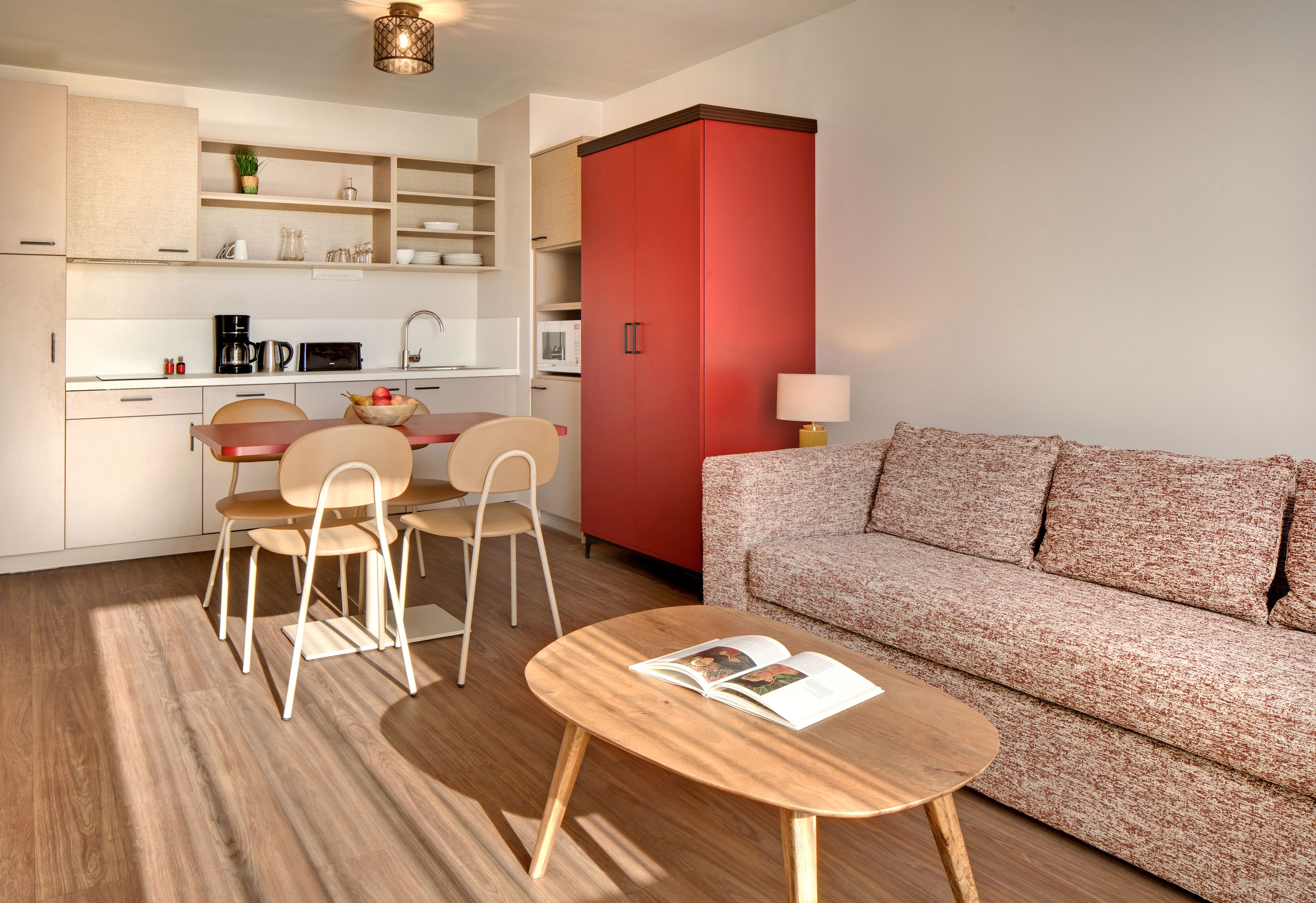 Un espace de vie compact comprenant une kitchenette, un coin repas et un coin salon.