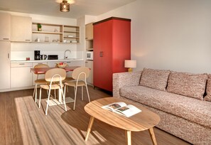 Un espacio habitable compacto con kitchenette, comedor y zona de estar.