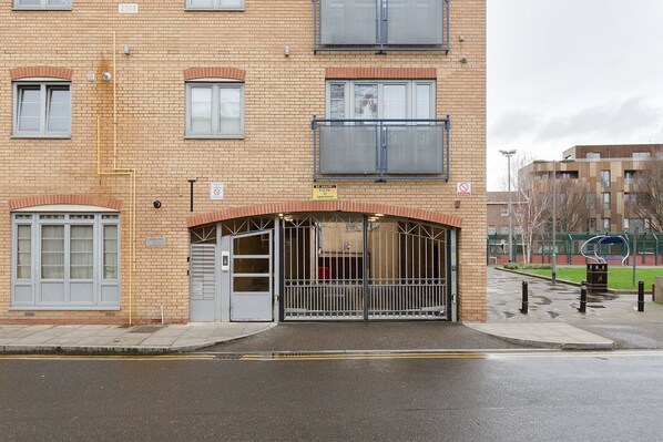 A brick building with a gated entrance, a sign indicating CCTV operation, and a no parking sign.