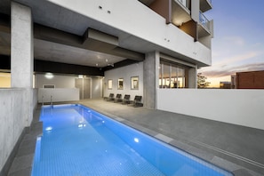 A modern building with a swimming pool, outdoor seating, and a view of the sunset. - Oaks Toowoomba Hotel (Toowoomba)