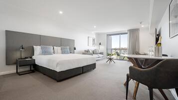 A modern hotel room with a large bed, a desk, and a view of the city.