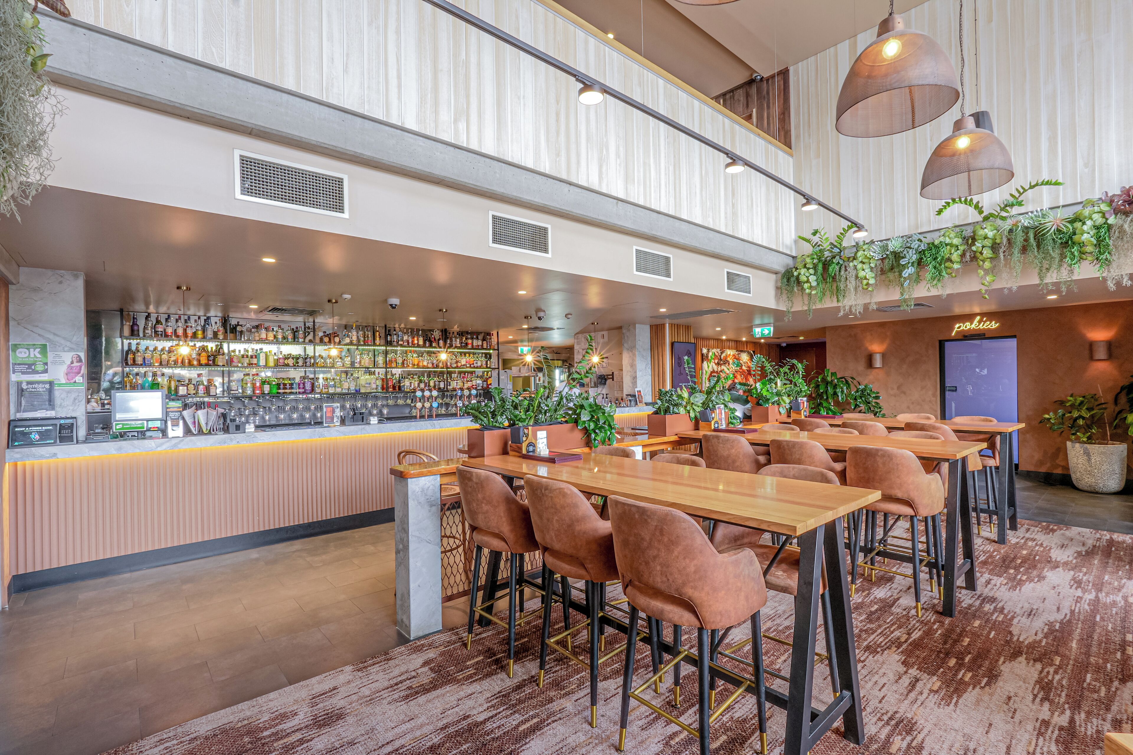 A bar area with a variety of liquor bottles, a cash register, and a seating area with tables and chairs.