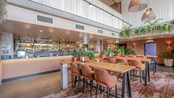 A bar area with a variety of liquor bottles, a cash register, and a seating area with tables and chairs.