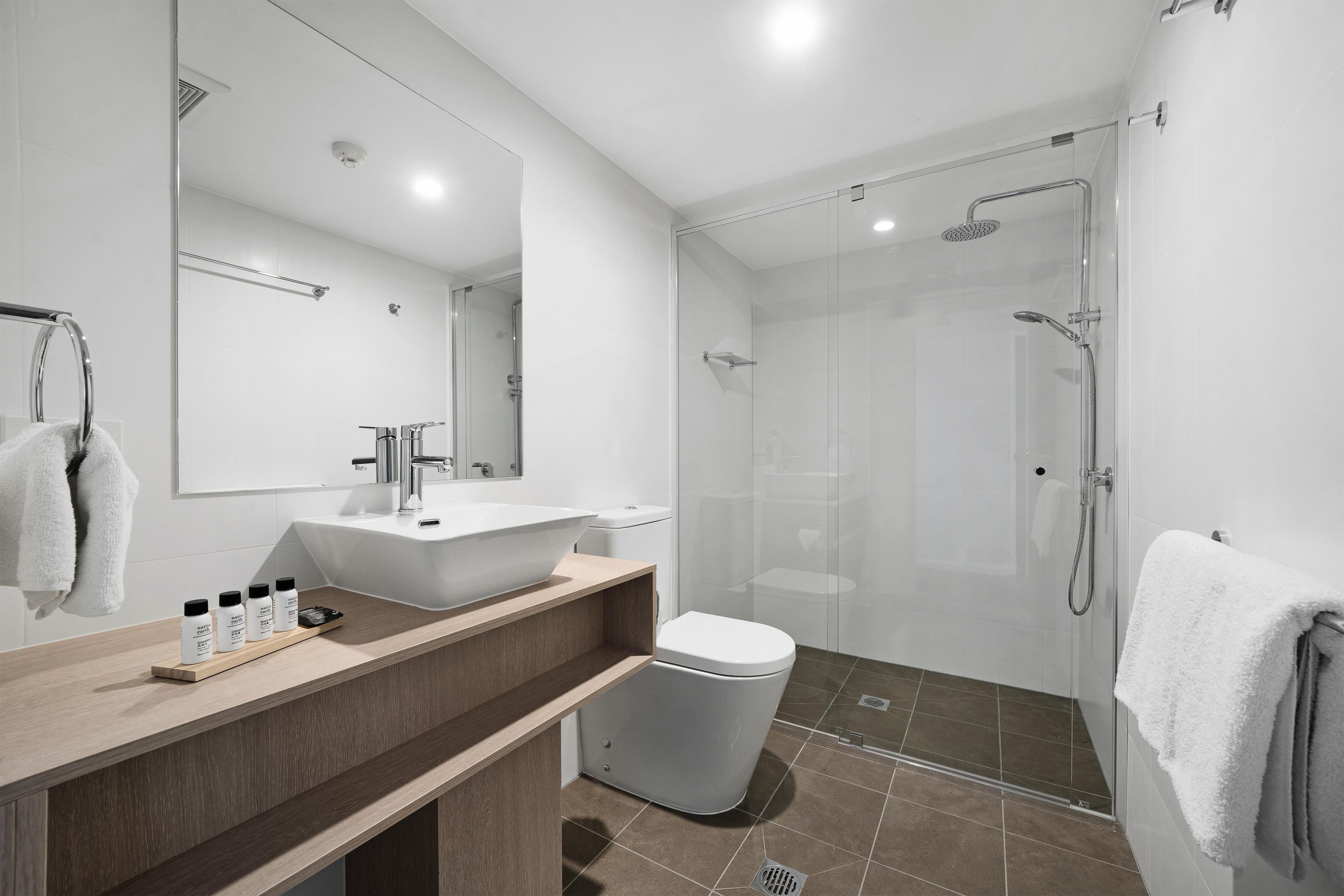 A modern bathroom with a glass-enclosed shower, a white sink, and a mirror above the vanity.