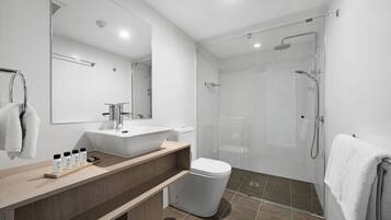 A modern bathroom with a glass-enclosed shower, a white sink, and a mirror above the vanity.