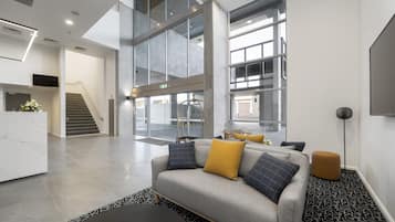 A modern interior with a grey sofa, a black coffee table, and a patterned rug.