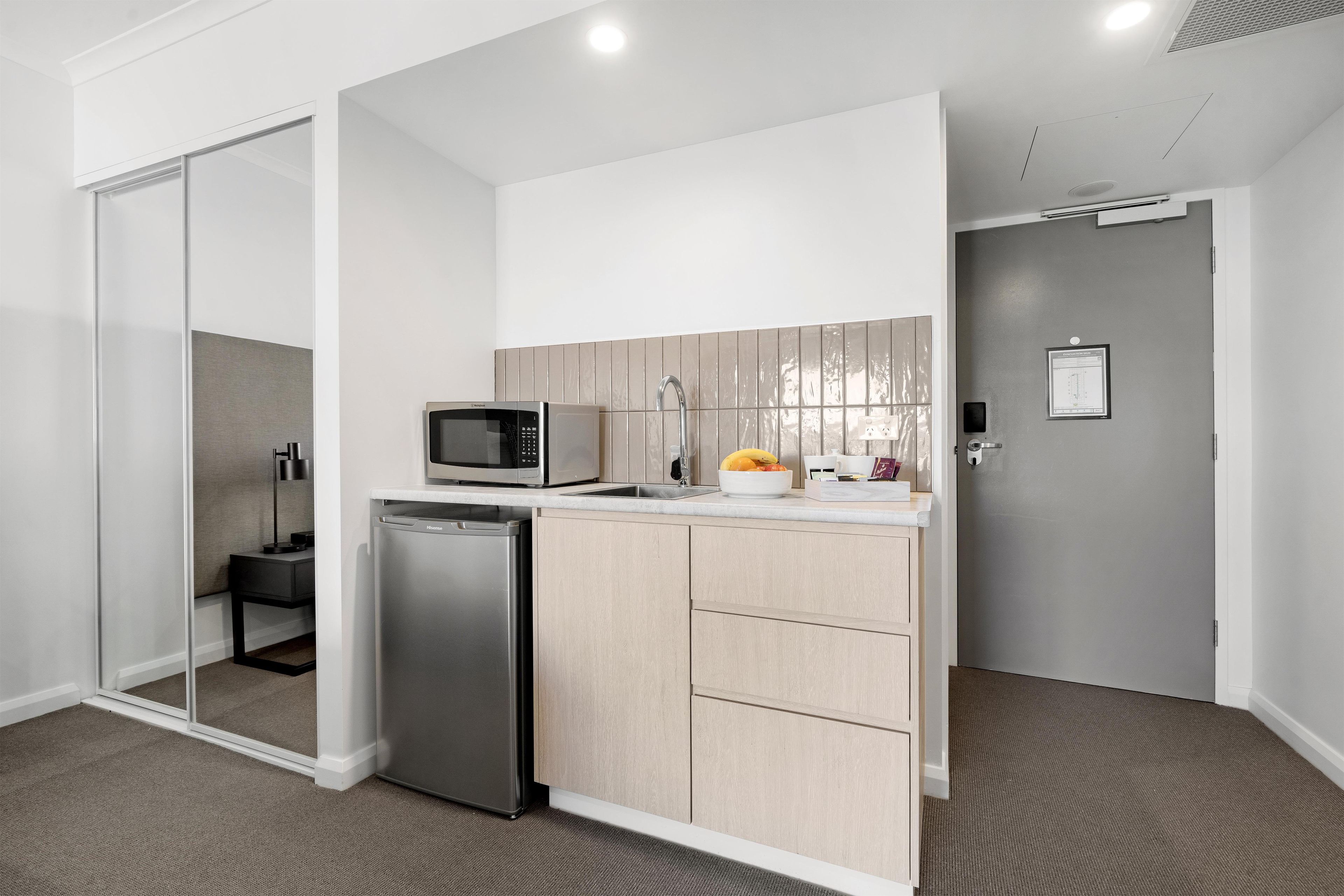 A compact kitchen with a refrigerator, microwave, and a small sink.