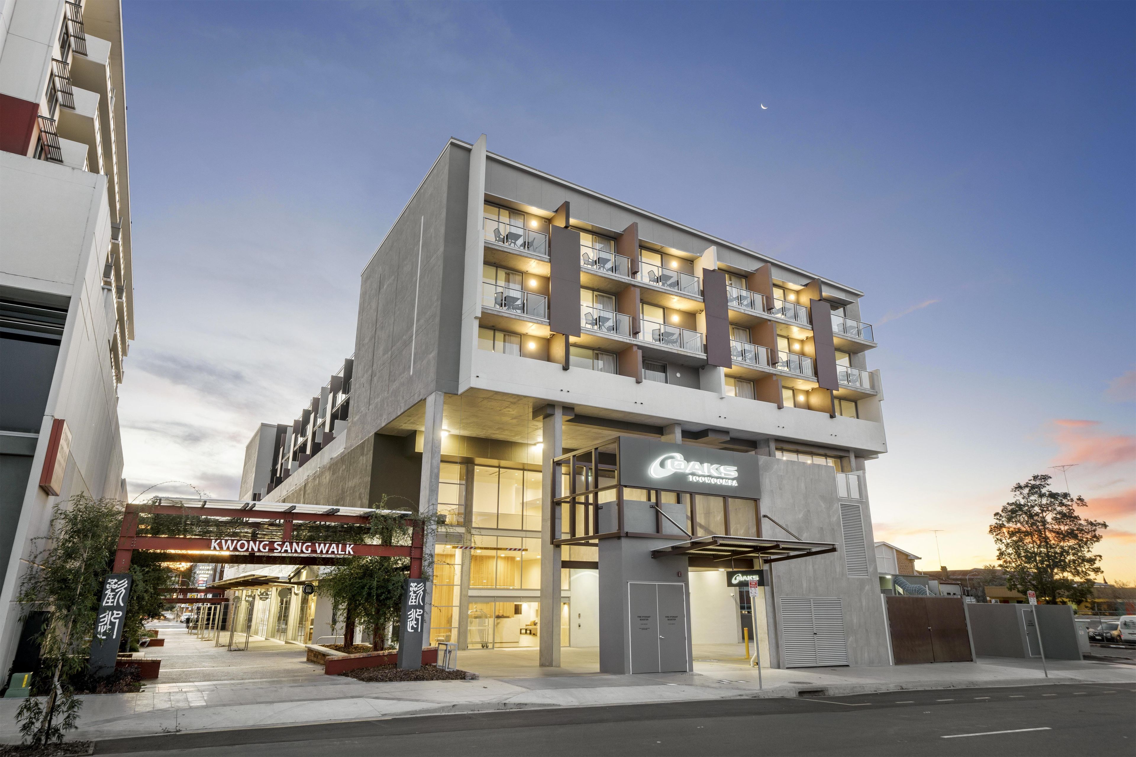 Un hôtel à plusieurs étages, doté d’un design moderne, avec des balcons à chaque étage, une entrée imposante et une signalétique indiquant le nom de l’hôtel.