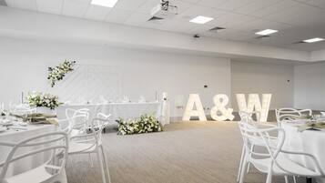 A conference room with white tables, chairs, and a floral arrangement.