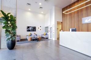 A modern hotel reception area with a white reception desk, a large potted plant, and a seating area with sofas and a coffee table. - Oaks Toowoomba Hotel (Toowoomba)