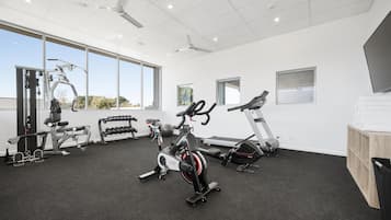 A gym with cardio machines, free weights, and a large window providing natural light.