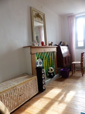 A room with a bed, a dresser, a mirror, a window with curtains, and a small panda decoration.