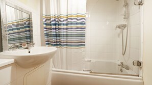 A bathroom with a bathtub, a sink, and a shower. - Bingley Court (Canterbury)