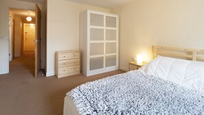 A bedroom with a bed, a dresser, a wardrobe, and a nightstand with a lamp. - Bingley Court (Canterbury)