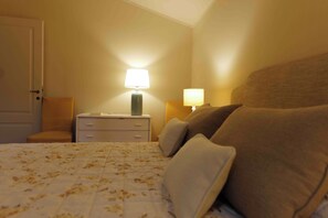 Quarto com uma cama, duas mesas de cabeceira e duas luminárias.