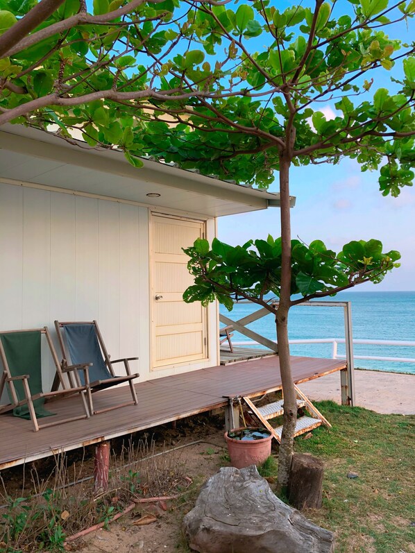 A beachside cabin with a wooden deck, two lounge chairs, and a view of the ocean. - Zhixianwu Homestay (Wangan)