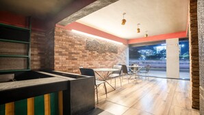 Een restaurantinterieur met bakstenen muren, een glazen scheiding en uitzicht op de straat.