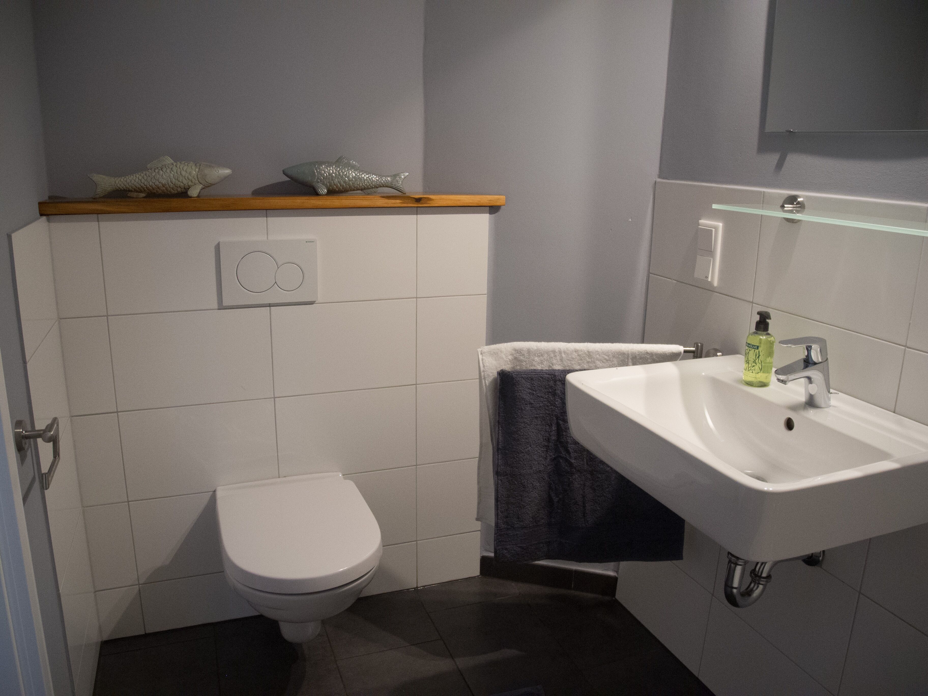 A bathroom with a white toilet, a sink with a mirror, and a towel rack.