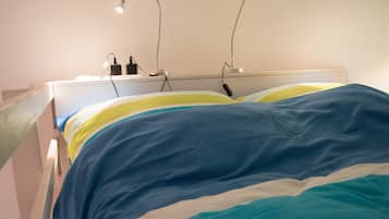 A bed with a white headboard and a colorful striped blanket.