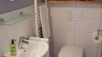 Une salle de bain avec un lavabo blanc, un bidet, un porte-serviettes et une étagère décorée de poissons.
