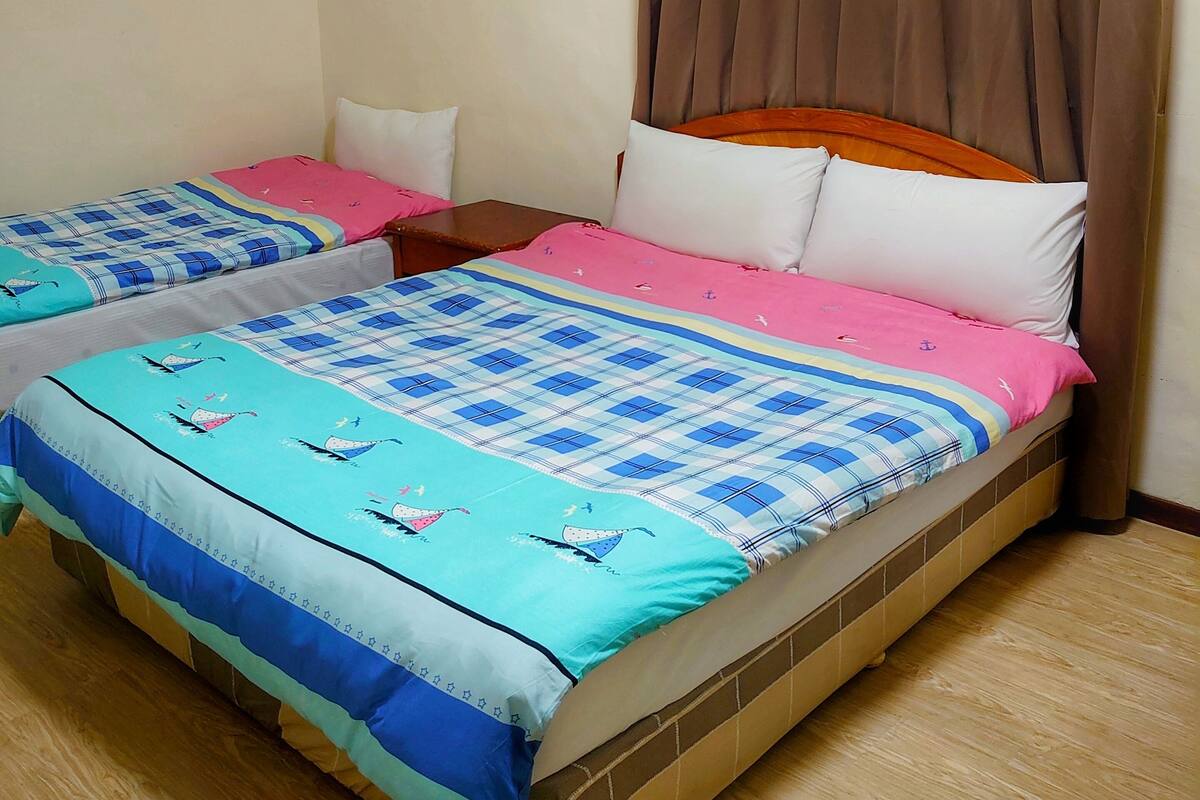 A room with two beds, each with a distinct patterned bedspread.