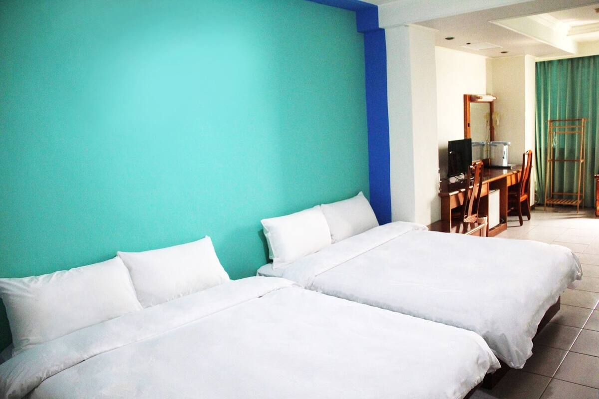 A hotel room with two beds, a desk with a computer, and a television.
