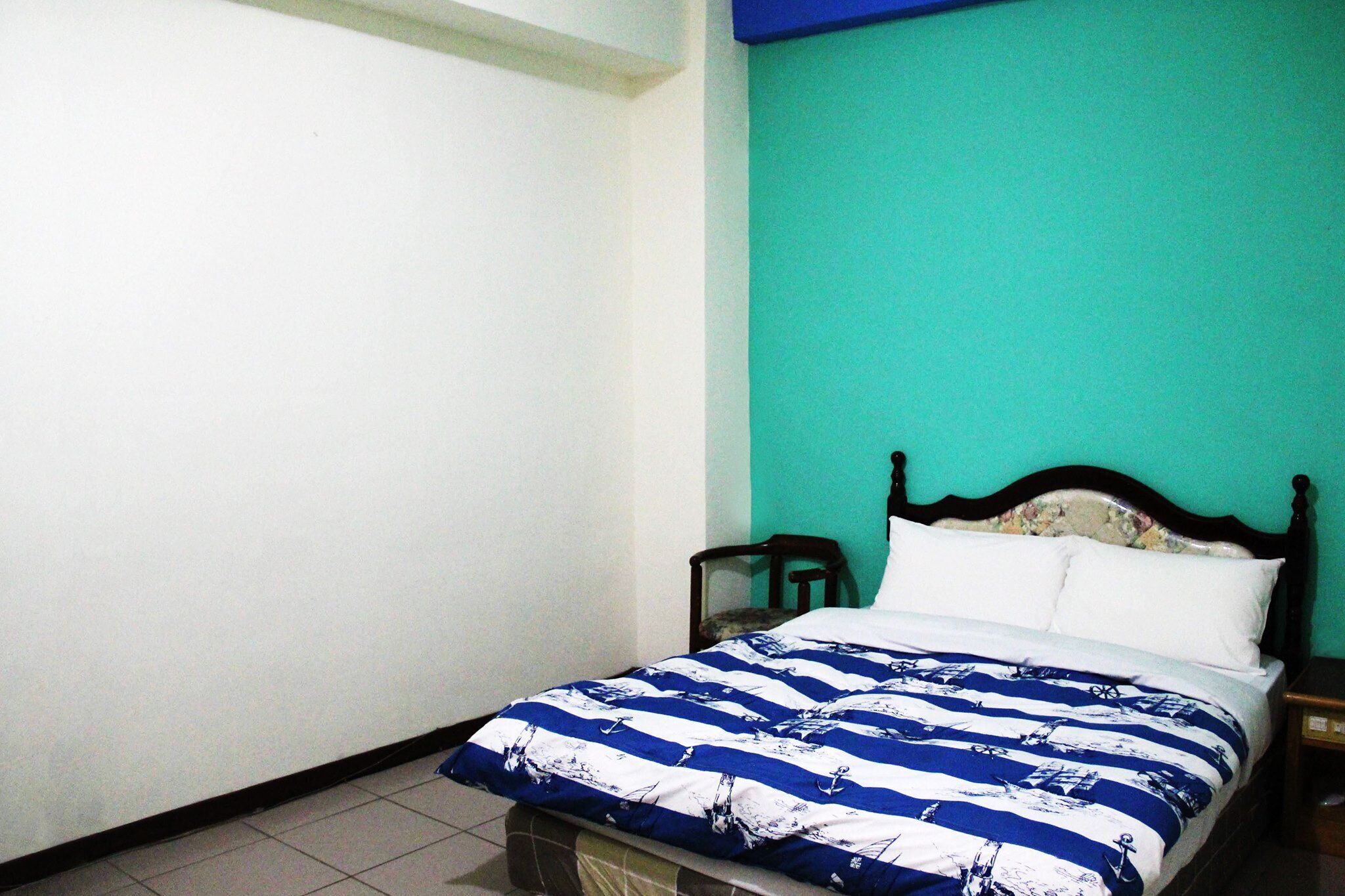 A bedroom with a bed, a chair, and a nightstand.