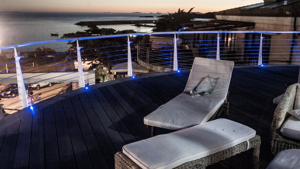 A rooftop terrace with lounge chairs and a view of the sea.
