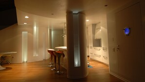 A modern interior with a central column, a round table, and two bar stools.