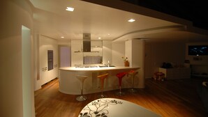 A modern kitchen with a central island, bar stools, and a dining table.