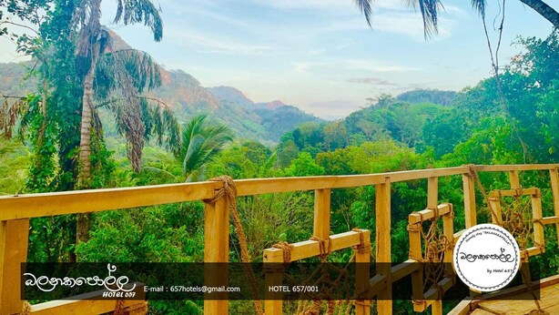 A wooden balcony with a view of lush green hills and palm trees. - Homely Stay Balana Kapolla (Mawanella)