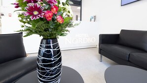 A modern hotel lobby with a black leather sofa, a round black table, and a decorative vase with flowers. - Hotel Nordbo (Nuuk)