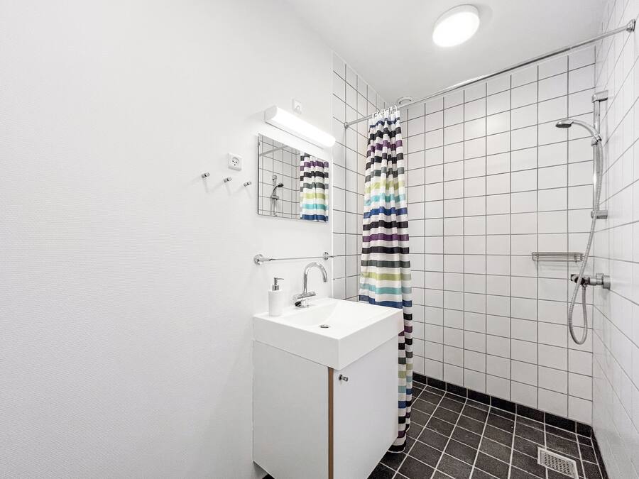 Un baño moderno con un lavabo blanco, espejo y ducha.
