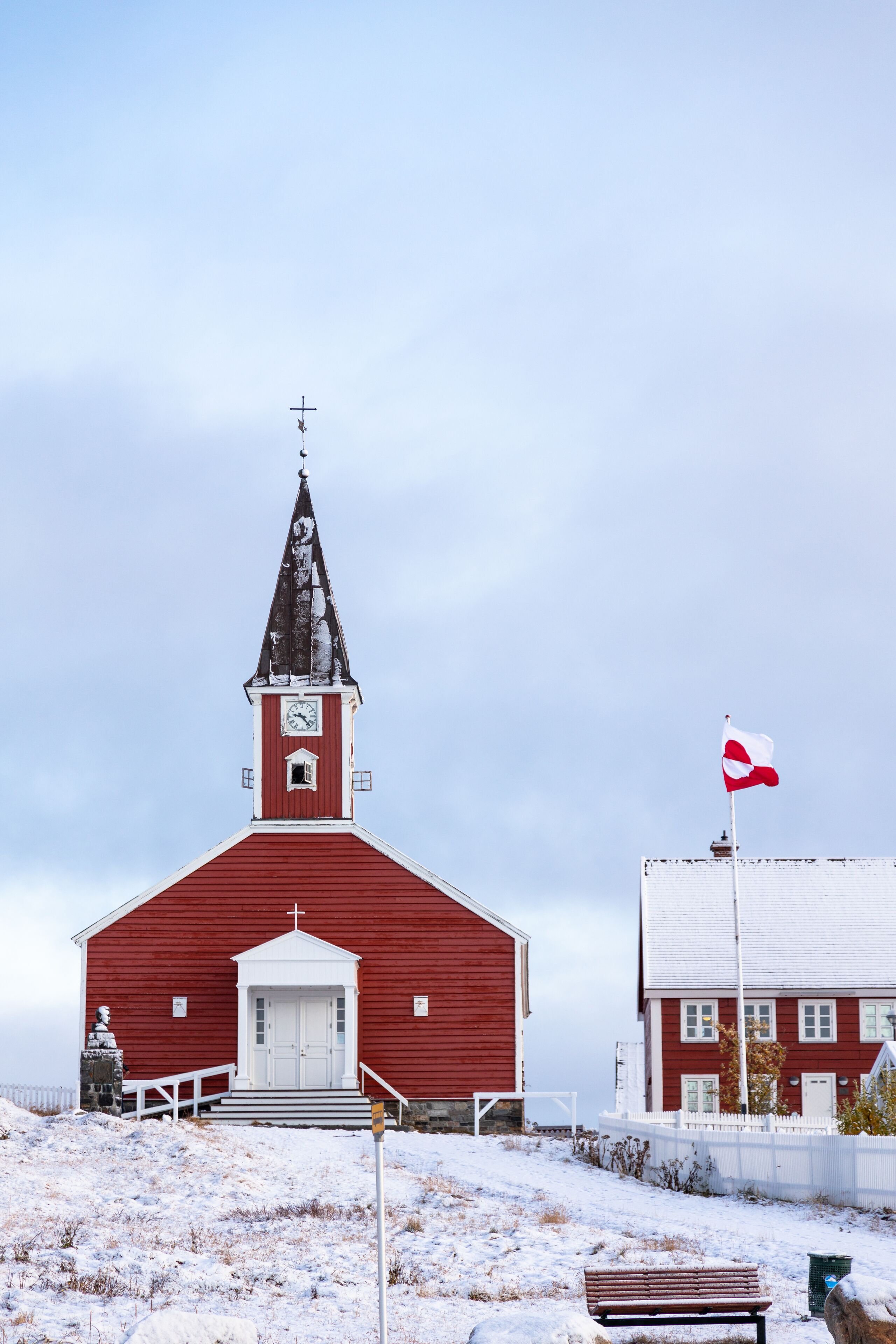 Una iglesia roja con campanario y un asta con bandera.