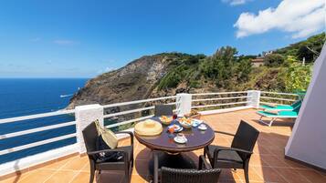 A terrace with a table set for breakfast, overlooking the sea.