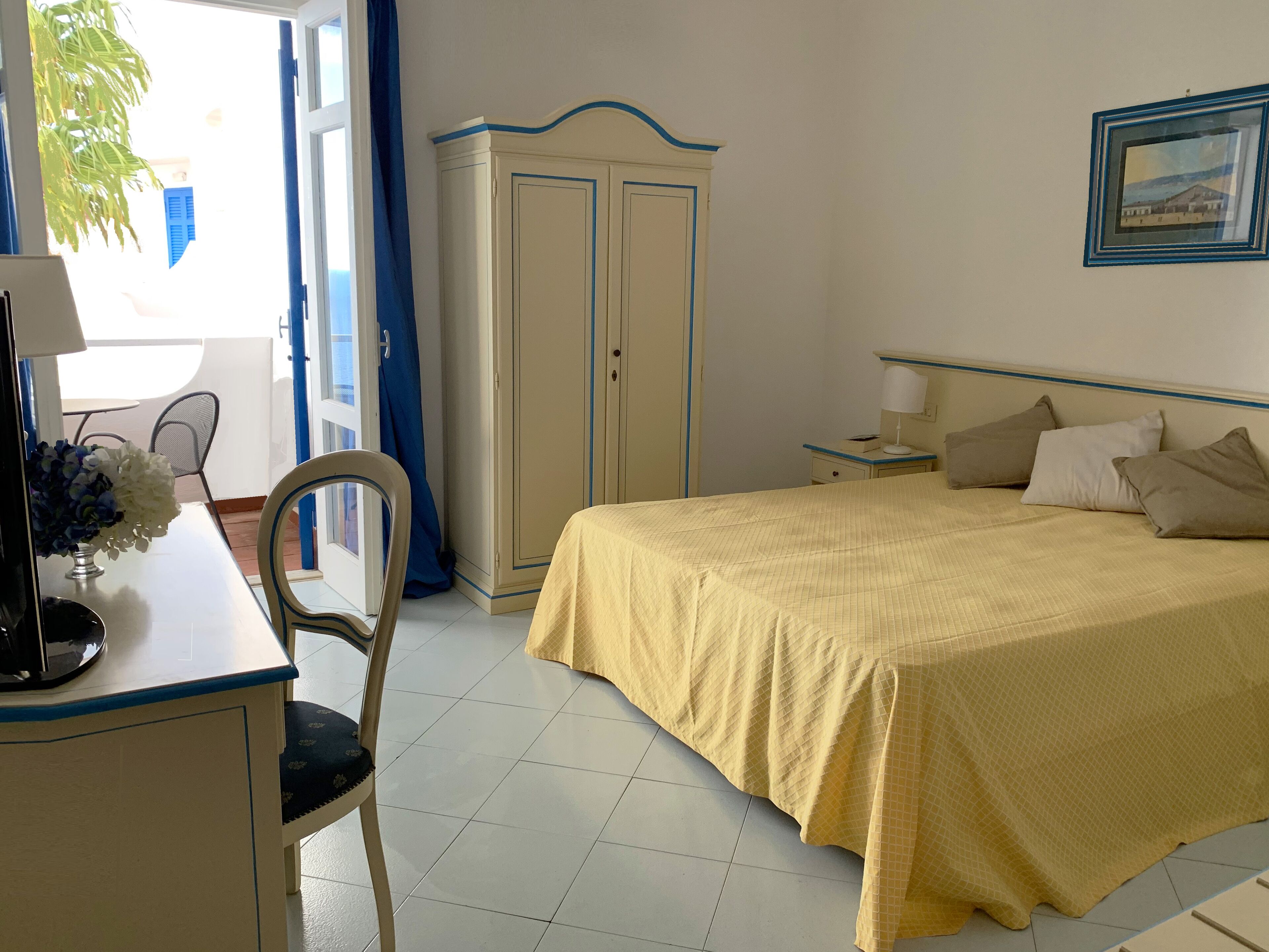 Habitación de hotel con cama, escritorio con silla, armario y ventana con cortinas.