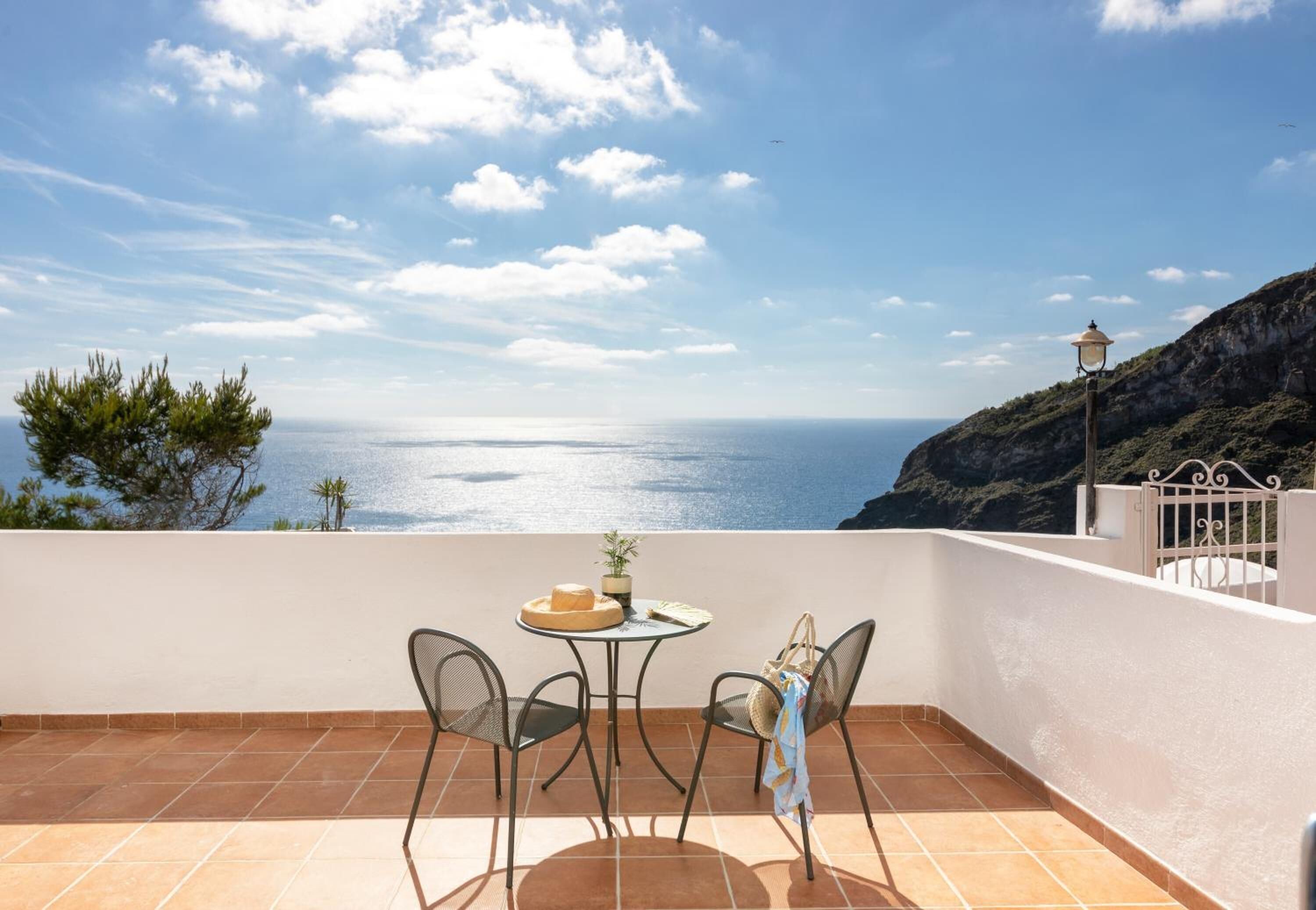 A terrace with a table and chairs, overlooking a coastal view with a lamp post.