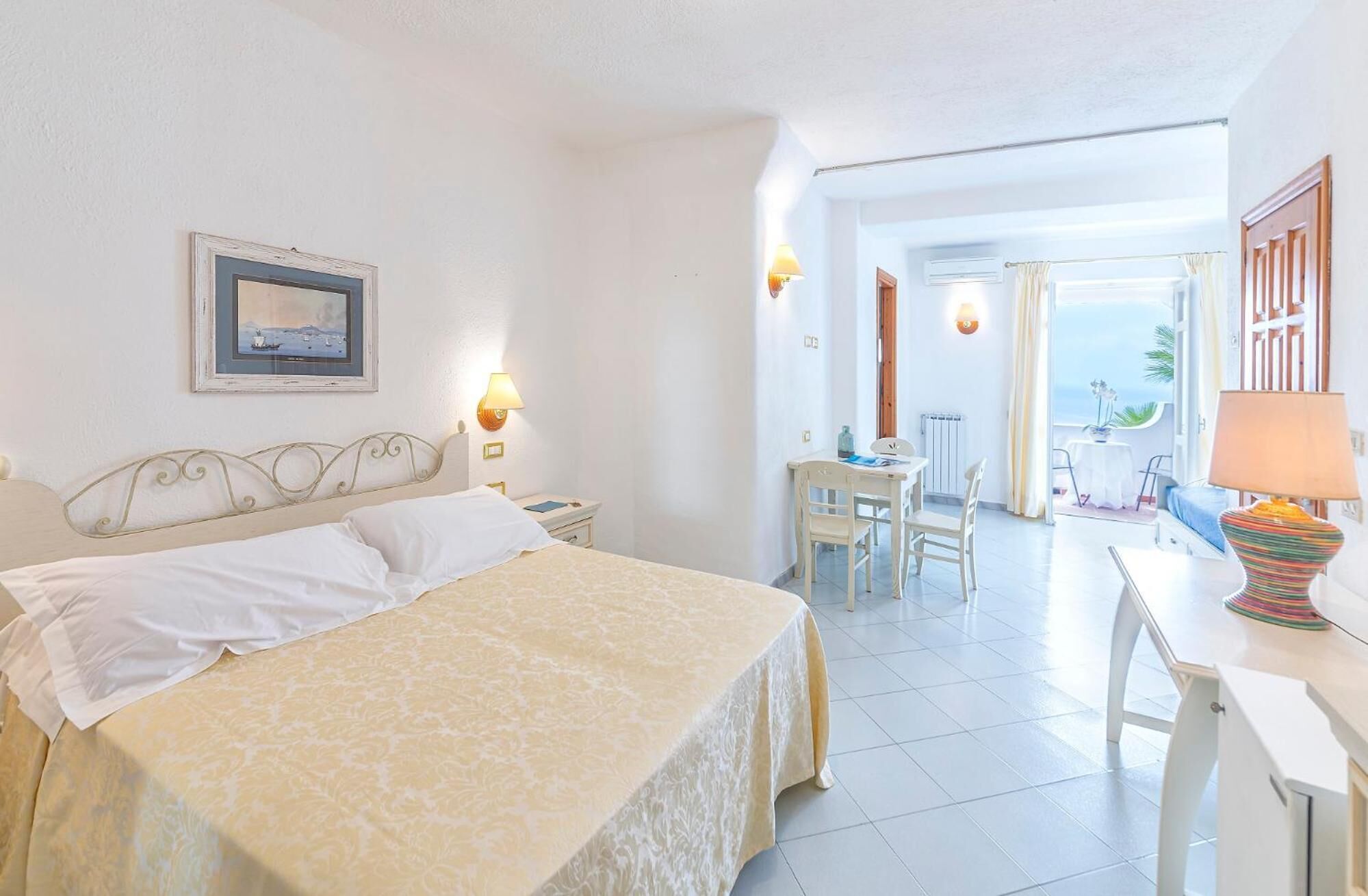 Habitación de hotel con cama, escritorio, silla y vista al mar.