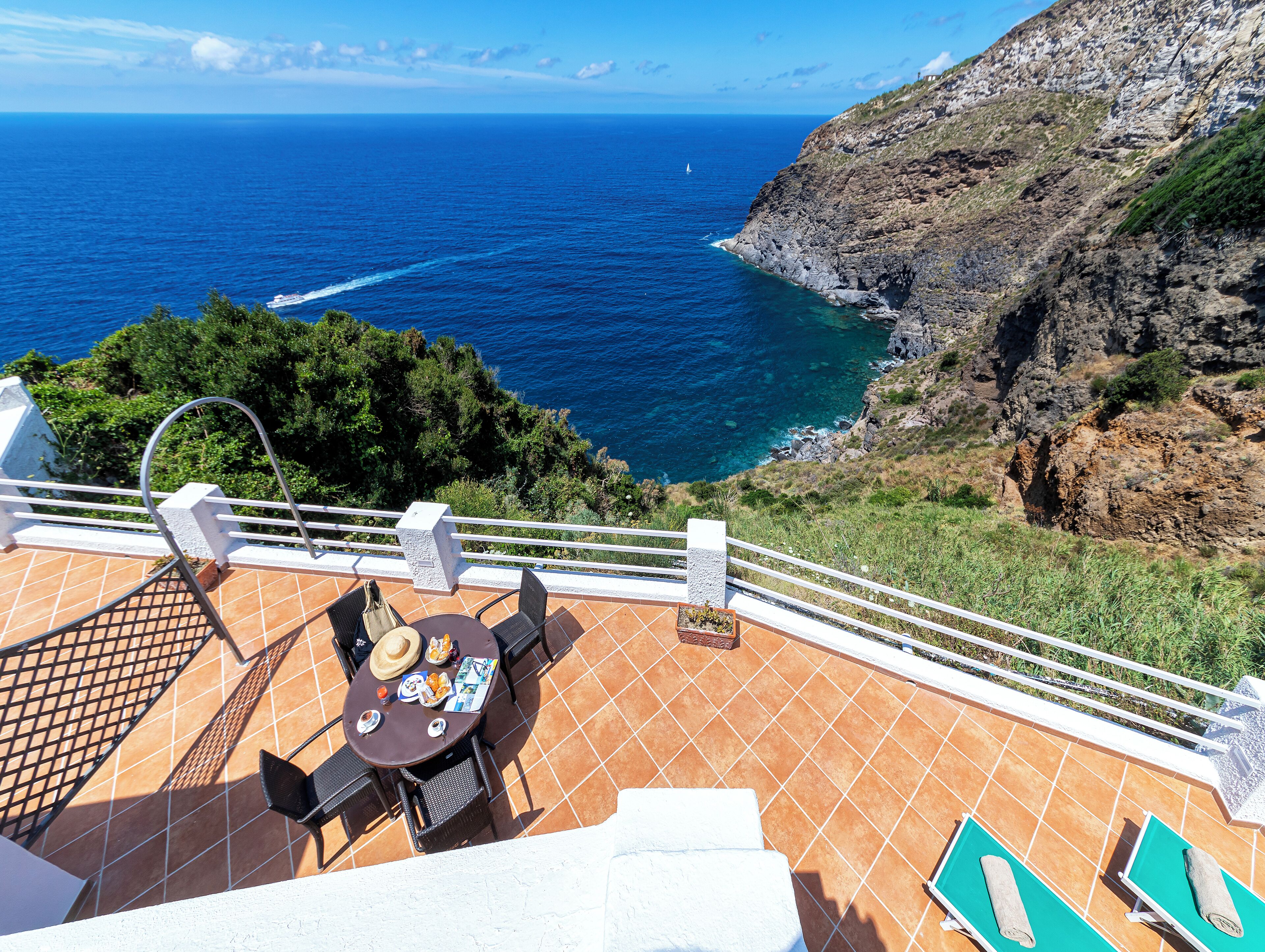 Une terrasse avec une table et des chaises donnant sur une falaise côtière et la mer.
