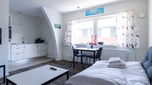 A modern hotel room with a bed, a small table, a desk, and a view of the outside. - Hotel Nordbo City (Nuuk)