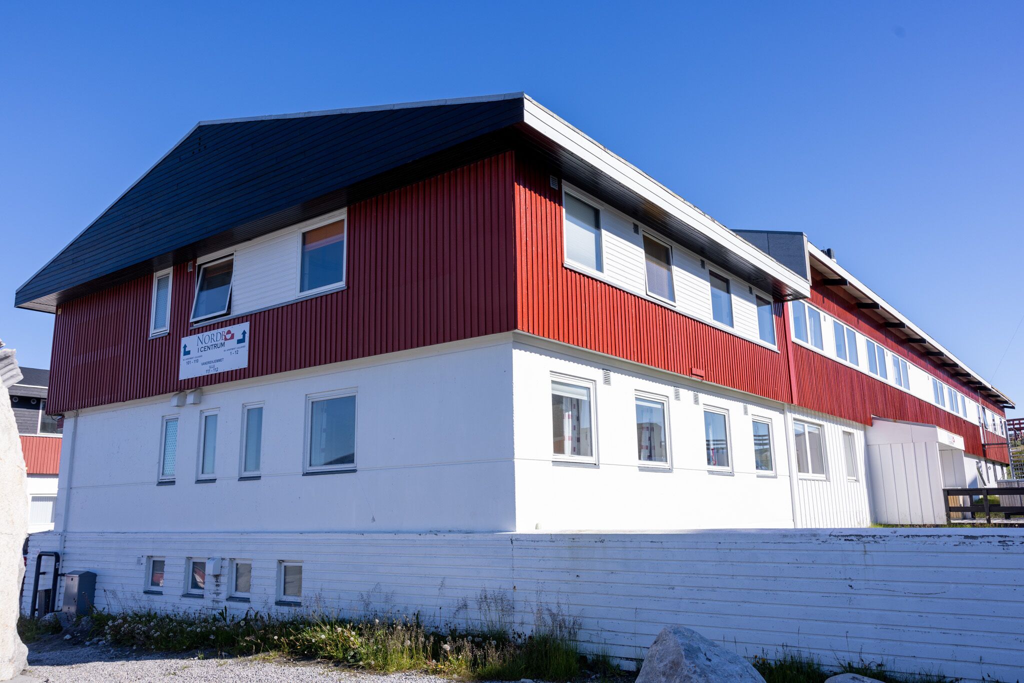Ein zweistöckiges Gebäude mit rotem und weißen Fassadenelementen, mit der Aufschrift "NORDIC CENTRUM".