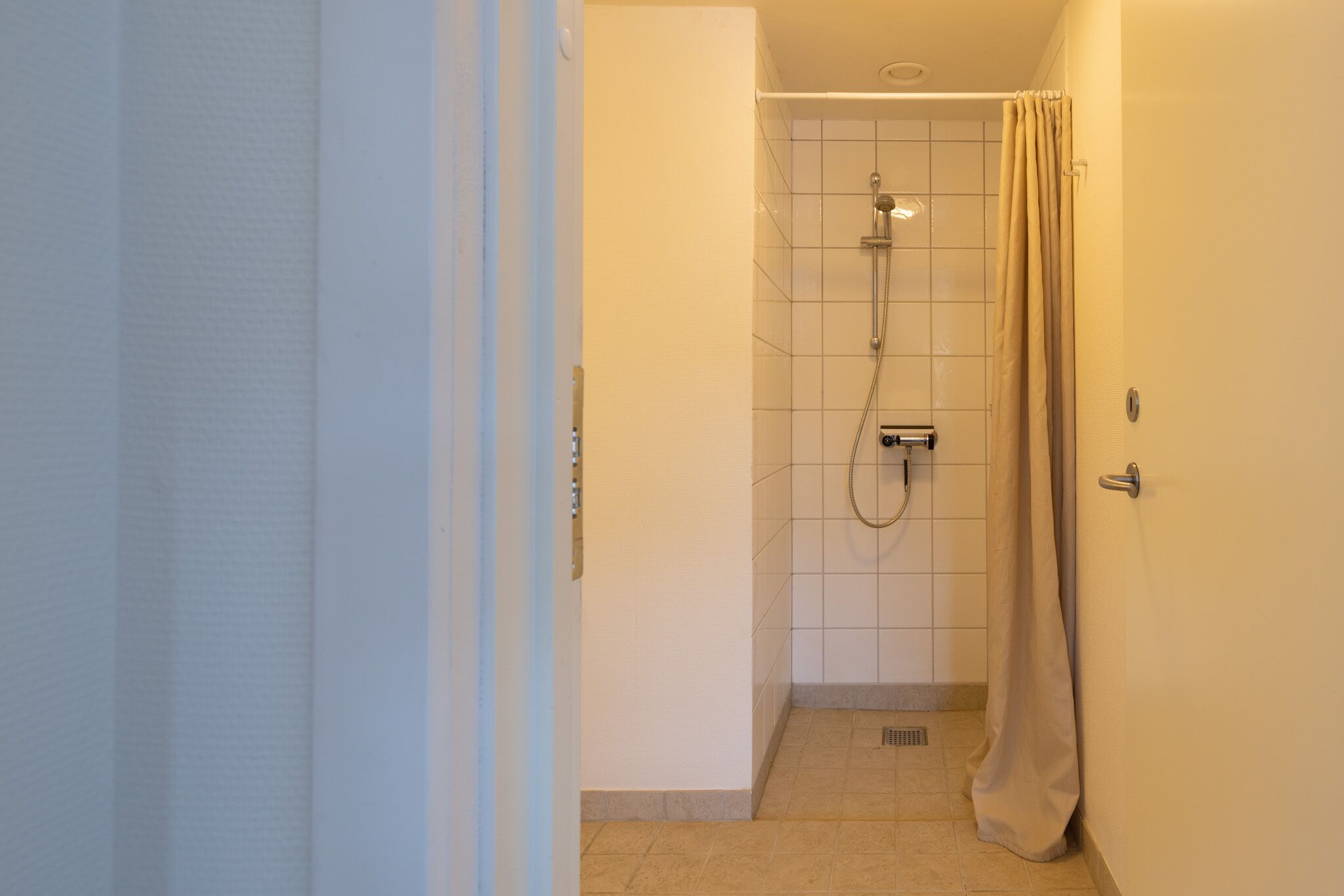 Un baño pequeño con azulejos, ducha, inodoro y lavamanos.