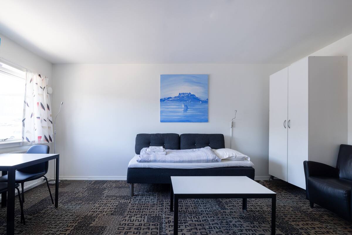 A modern room with a bed, a desk, a chair, and a wardrobe.